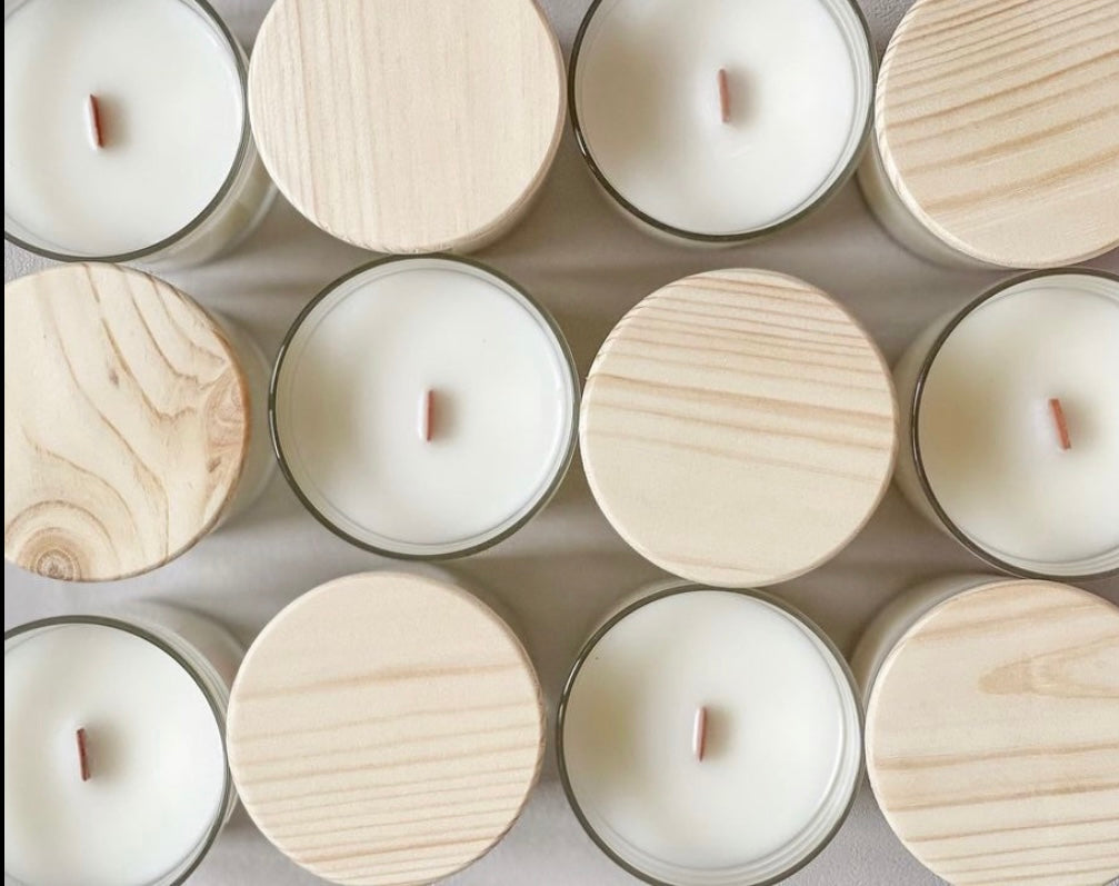 Twelve candles in glass jars with wood wicks and wooden lids.