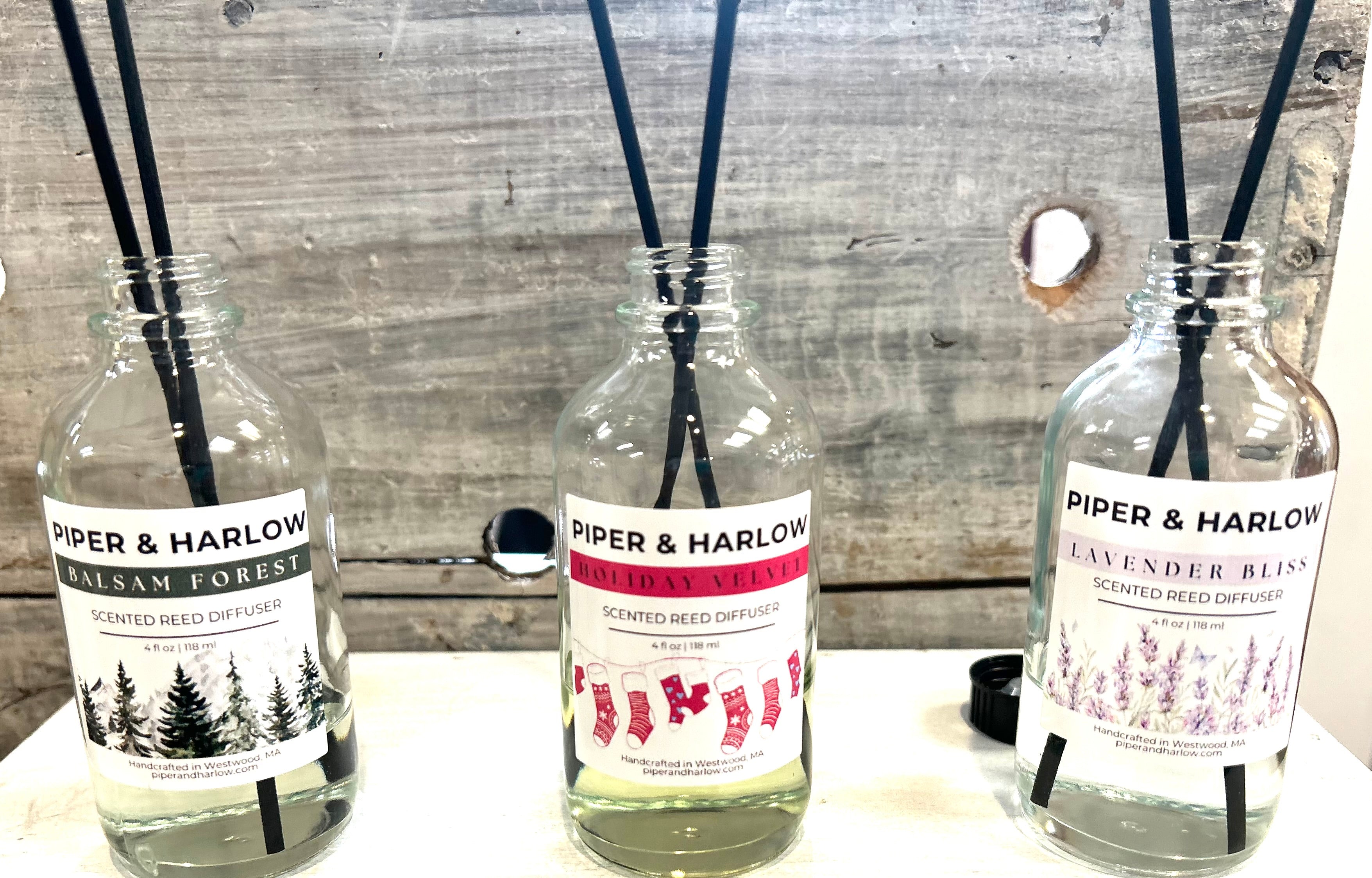 Three bottles of Piper & Harlow diffusers on a wooden surface