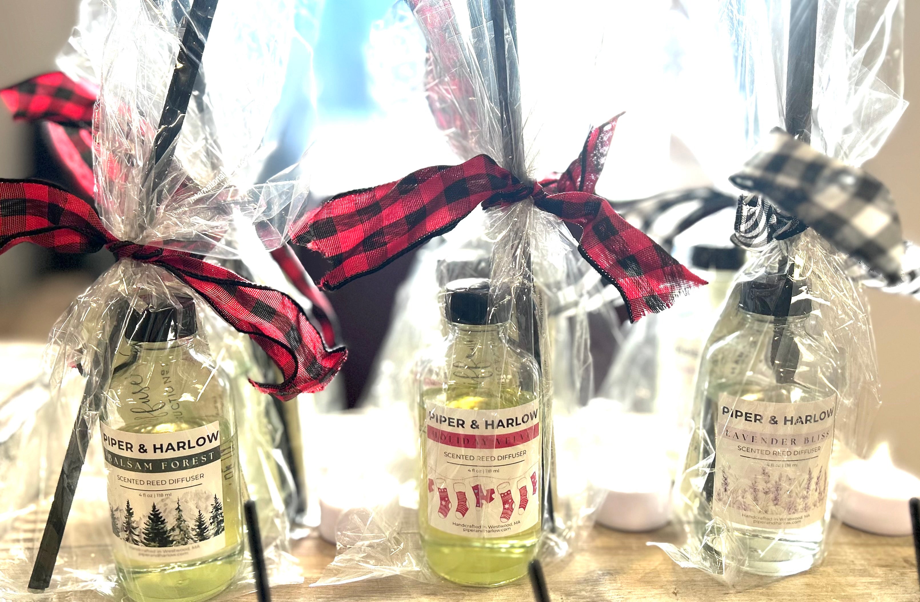 Three bottles of Piper & Harlow products wrapped in cellophane with ribbons on a table.